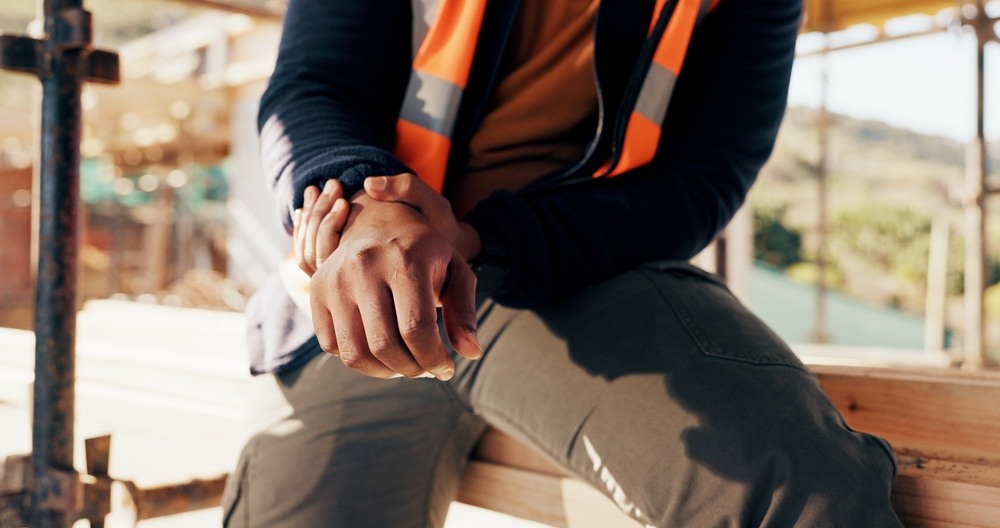 Construction worker sitting with clasped hands, representing a work-related hand or wrist injury claim