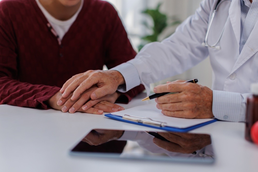 Doctor placing a reassuring hand on a patient while documenting a diagnosis, representing an occupational illness workers' comp claim